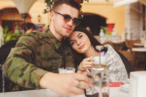 Couple in love sit in cafe outdoor, urban background.
