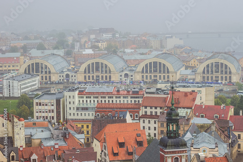 Aerial view of pavilions of Riga Central Market from Saint Peter church on foggy and rainy day. Europe's largest bazar using old German Zeppelin hangars, Riga, Latvia. Soft selective focus
