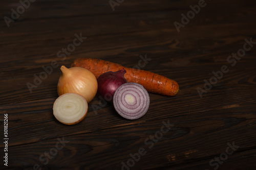 vegetables on a wooden deified table. red variety and white onion, whole onions and carrot photo