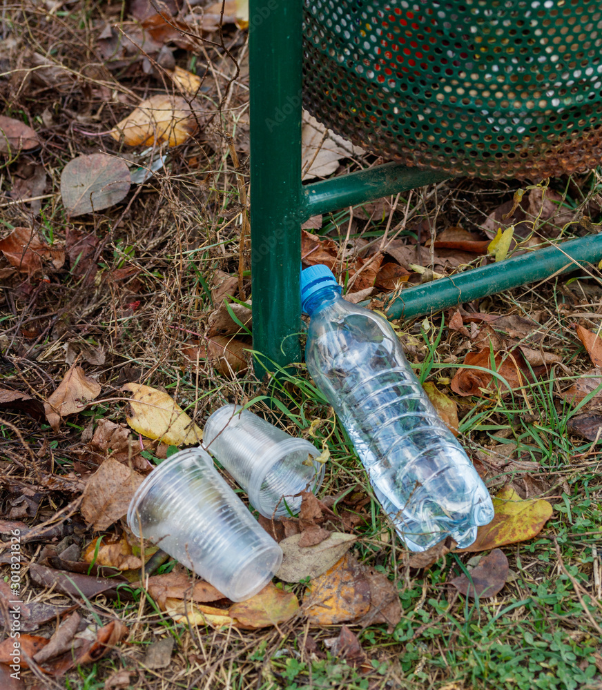 Obraz premium plastic bottle and plastic glasses near the trash can