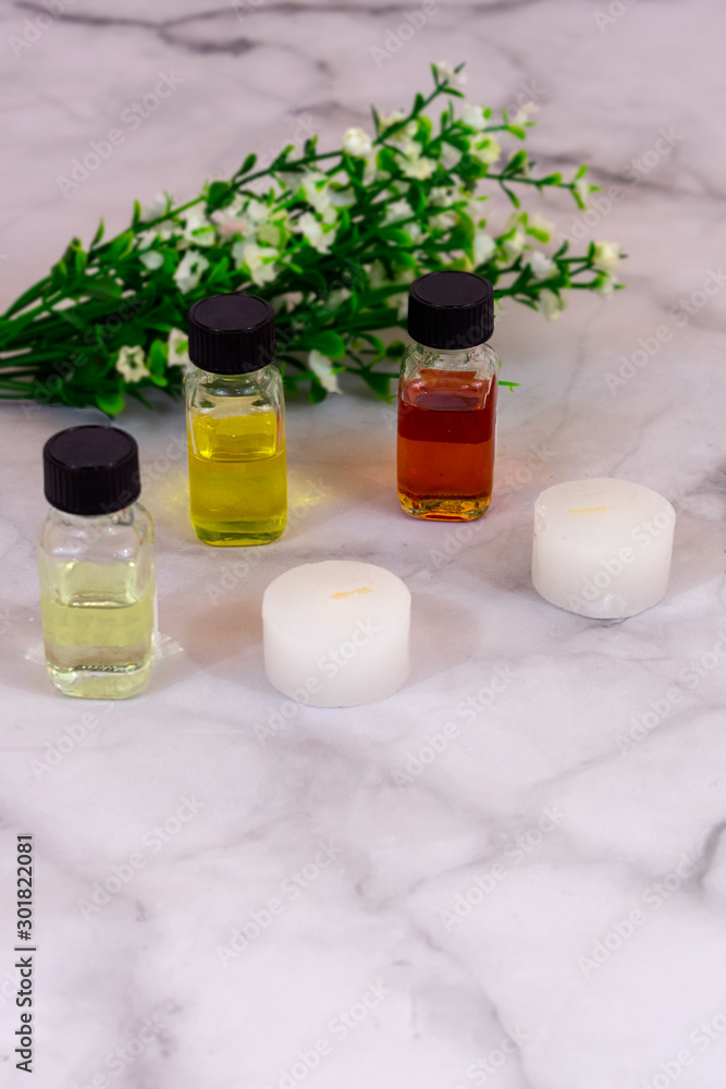 Essential oils over marble background with white flowers and copy space in portrait position. Flat lay 