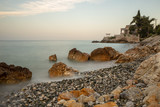 Sea coast with textured rocks and pebbles in the water. Long exposure shot.