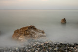 Sea coast with textured rocks and pebbles in the water. Long exposure shot.