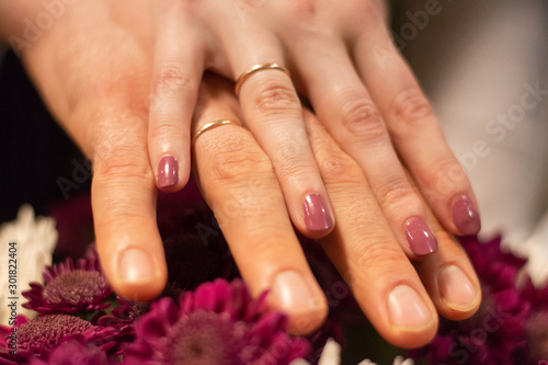 hands of the wife and husband after the wedding, wedding rings on the fingers. hands are on the flowers
