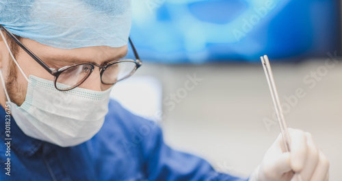 young surgeon with glasses is operating with surgical instruments.