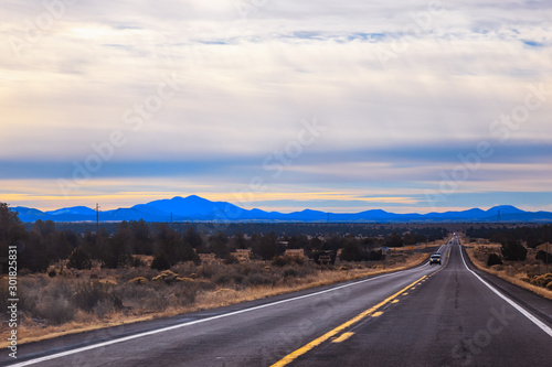 Long road/freeway US-89 N, towards Flagstaff, Arizona, USA. Mountains at the horizon. Early winter morning road trip/vacation/travel scenery background. 