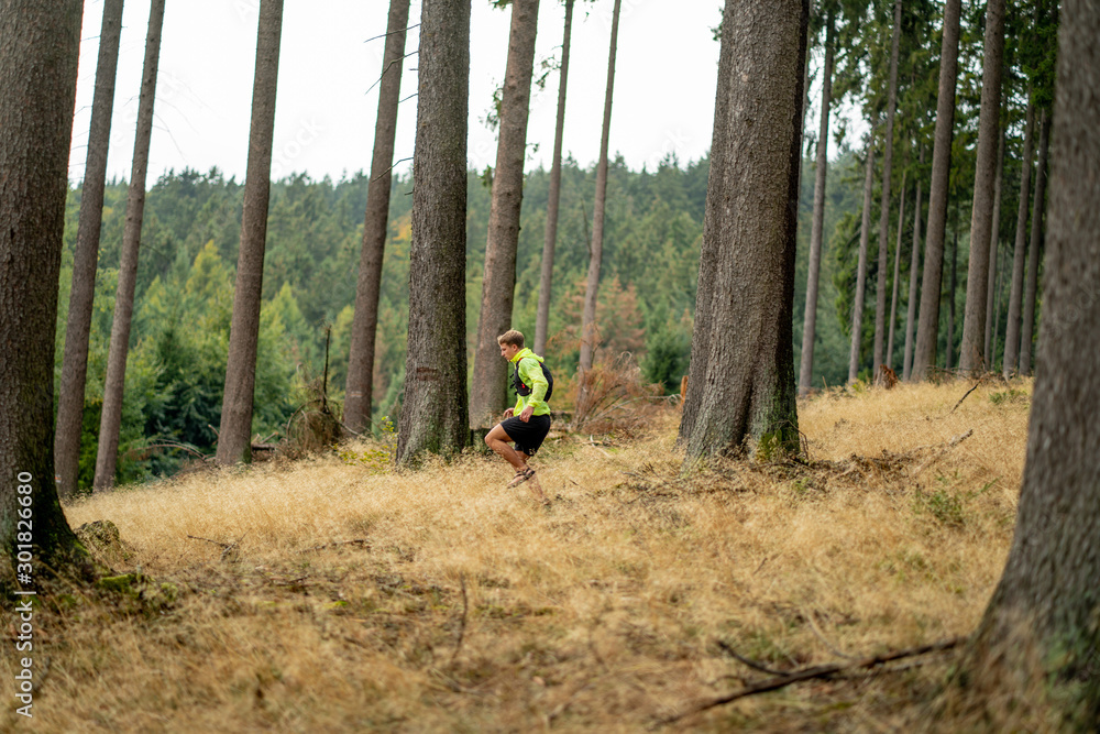 A young athlete in barefoot shoes runs down the mountain. Mountain run. Cross Country Running. Individual sports A young athlete in barefoot shoes runs down the mountain. Mountain run. Cross Country Running. Individual sports