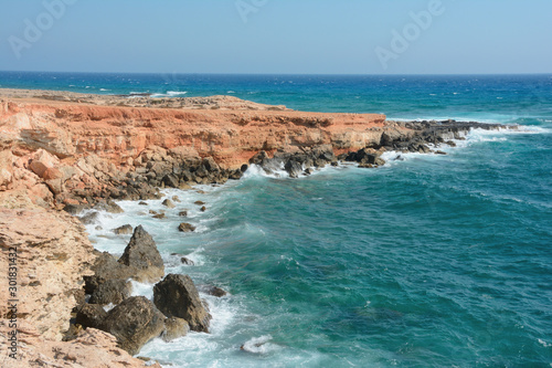 Rocky sea shore with waves and beautiful water, clear blue sky photo