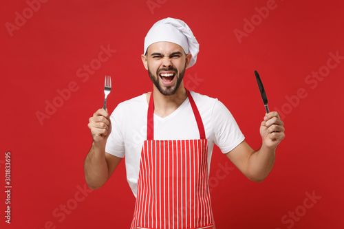 Crazy young bearded male chef cook or baker man in striped apron toque chefs ...