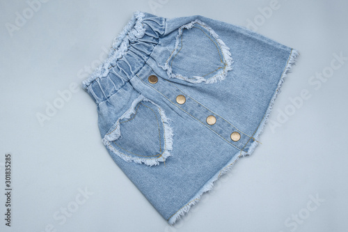 Children's stylish jeans blue color skirt on grey background. Top view
