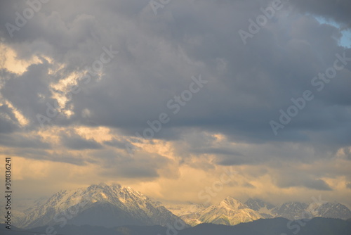 North caucasus mountains in the rays of light around clouds. Snowy mountain ridge peaks.
