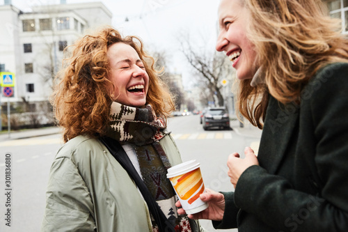 Two girls chatting on the street of the Moscow city happy and laughing