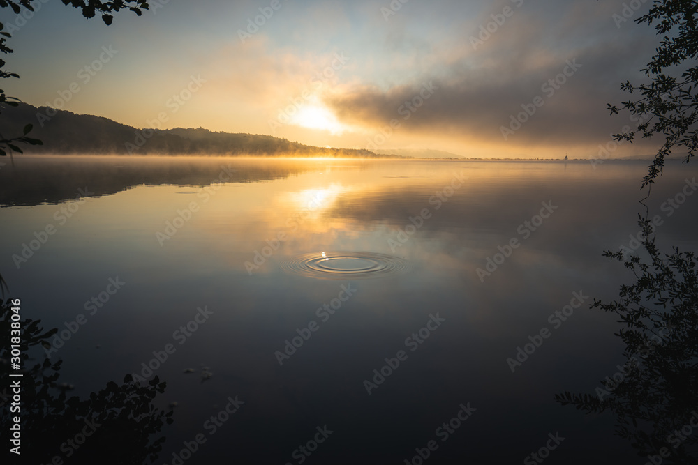 Sonnenaufgang am See mit Dunst über dem See