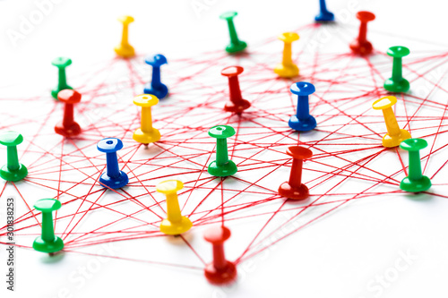 Network with colorful pins and string, linked together with string on a white background suggesting a network of connections.