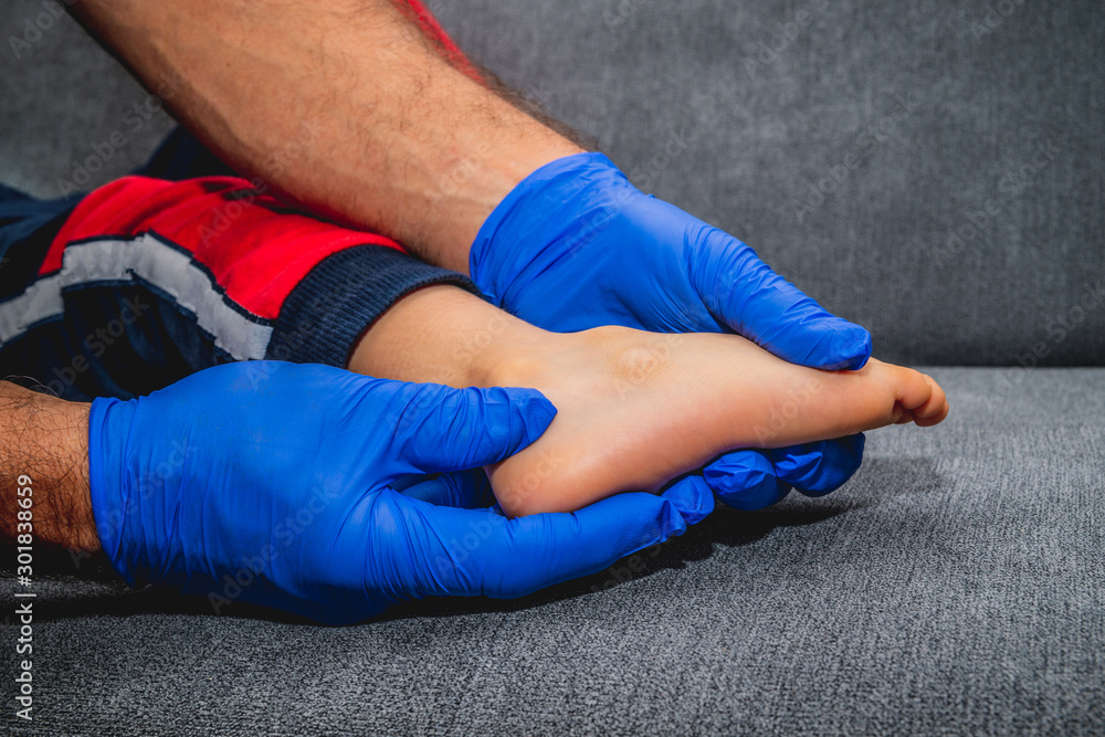 Ankle pain in a child. The doctor checks the leg of a small patient. Medical and pharmaceutical concept, leg fracture or dislocation. Ankle pain in a child. The doctor checks the leg of a small patient. Medical and pharmaceutical concept, leg fracture or dislocation.