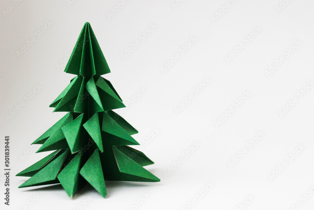Origami green tree in the left corner of the photo on a white background Origami green tree in the left corner of the photo on a white background