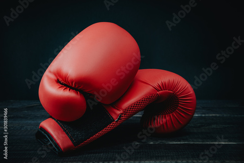 Red boxing gloves on wooden background. The concept of sport and active leisure. On the table are red boxing gloves, kickboxing. Playing sports, taking care of your figure, fight and self-defense. © Sebastian