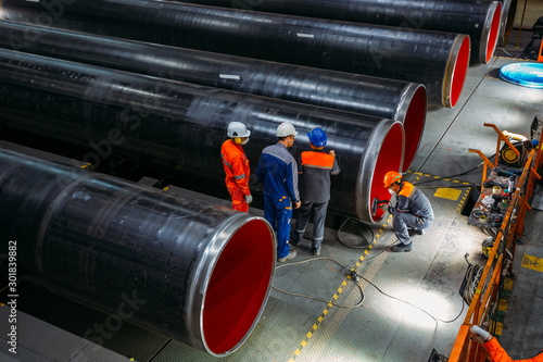 Canvas-taulu Engineers examine new coated pipe in factory