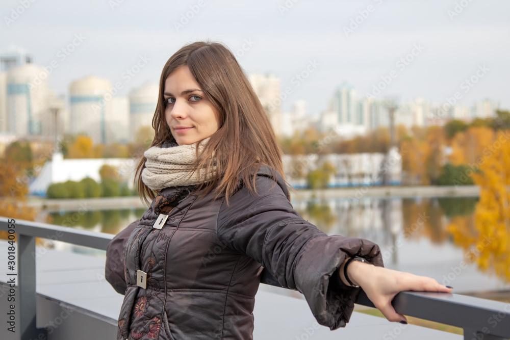 A pretty girl is standing on the observation deck in the city. A young woman and Autumn walk around the city.
