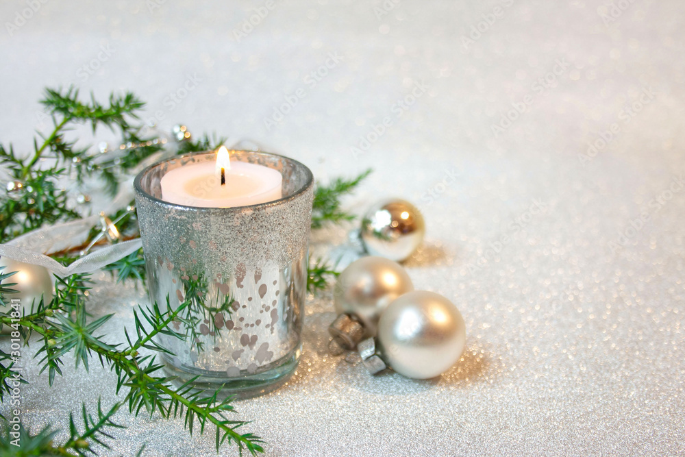 Fototapeta premium Srebrne bożonarodzeniowe tło ze świecą, bombkami i gałązkami jałowca