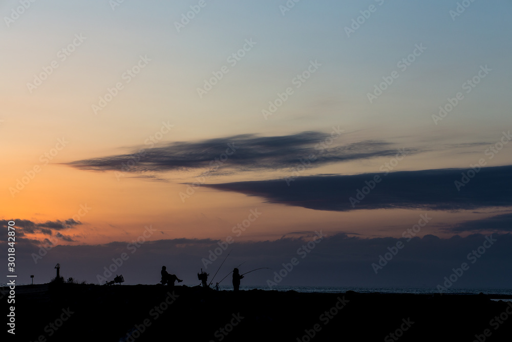 Fishermen silhouette on a sunset landscape on an orange sky in La Camargue, France Fishermen silhouette on a sunset landscape on an orange sky in La Camargue, France
