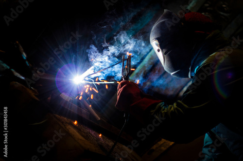 welder doing metal work at night, front and background blurred with bokeh effect
