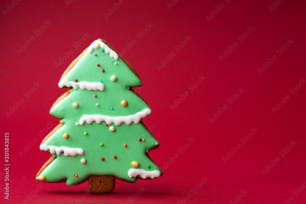 gingerbread cookie of green Christmas Tree on red background. Traditional Christmas food. Christmas and New Year holiday concept. Copyspace gingerbread cookie of green Christmas Tree on red background. Traditional Christmas food. Christmas and New Year holiday concept. Copyspace