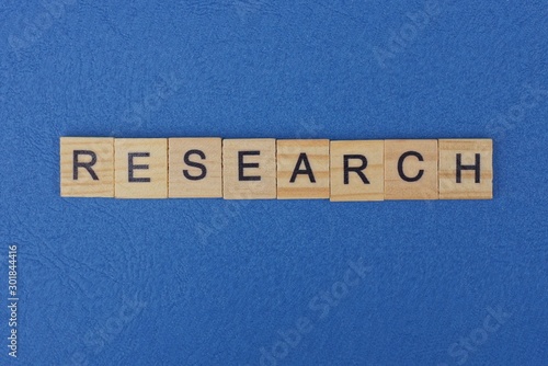 word research made from brown wooden letters lies on a blue table