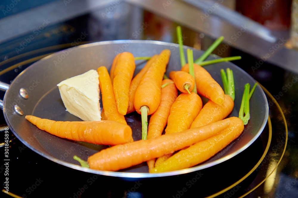Whole young carrots are fried with butter in a skillet. Whole young carrots are fried with butter in a skillet.