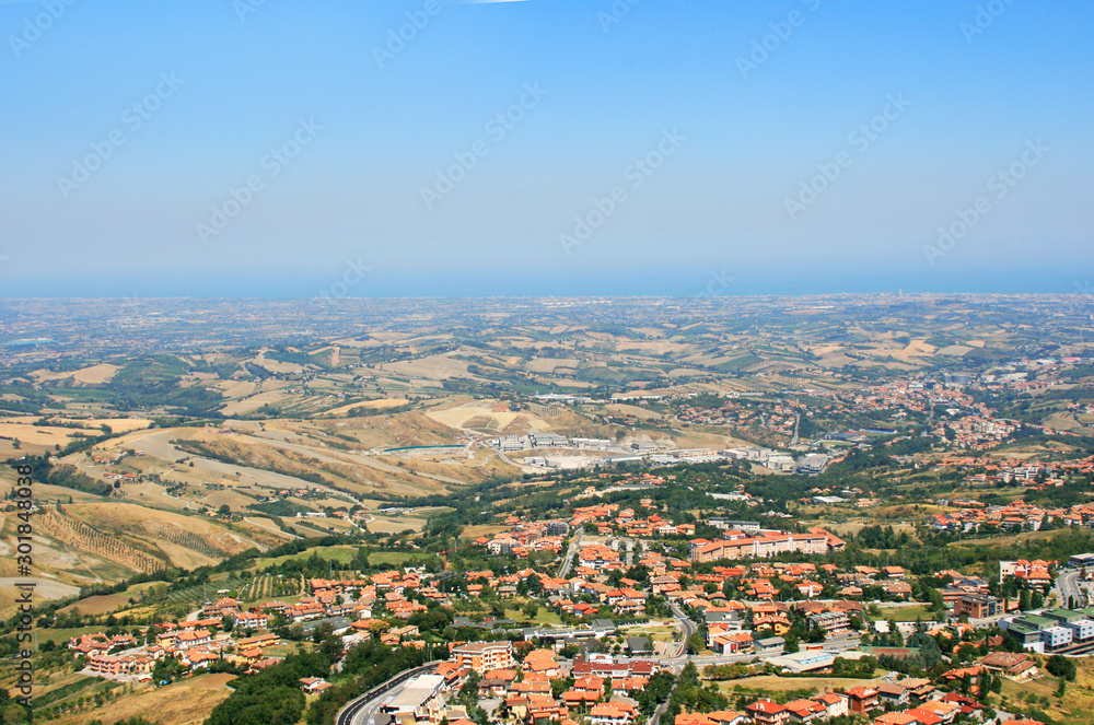 Amazing Italian mountain landscape with blue airways, red roofs of houses in the valley, bright blue southern sky