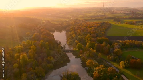 Aerial footage during late Fall Autumn of a river reflecting the sunset over rural England in the countryside, West Yorkshire, UK - Wakefield