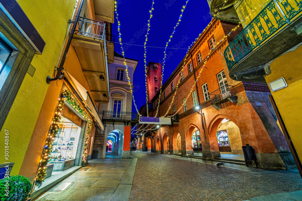 Cobblestone pedestrian street with Christmas illumination in Alba, Italy.