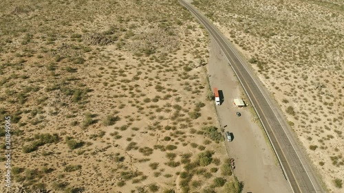 Aerial footage from a drone flying over a highway extending into the desert of Arizona as the camera slowly pivots from looking down to looking up. photo