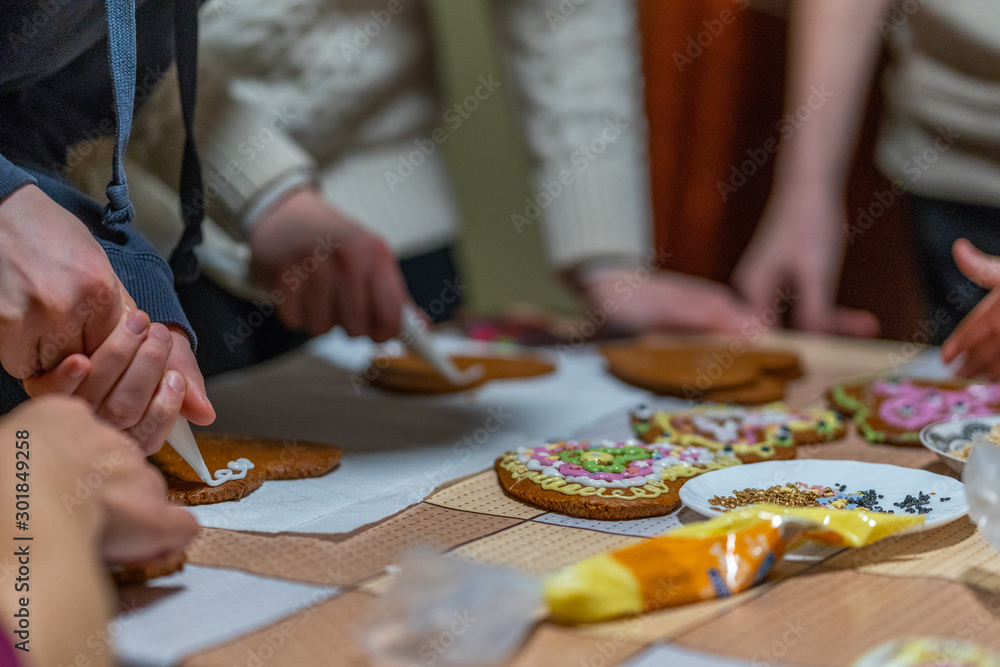 Wide angle shot of family putting icing on heart shaped gingerbread cookies Wide angle shot of family putting icing on heart shaped gingerbread cookies