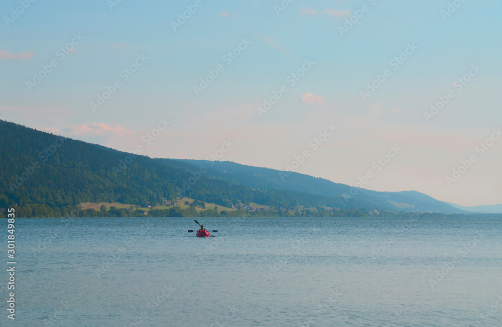 People floating in an inflatable red boat and paddling. Mountain lake Zhu in Switzerland.