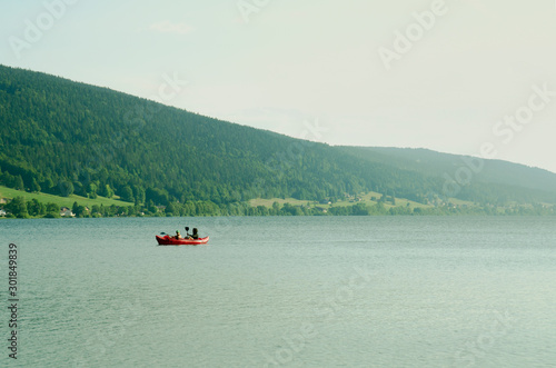 People floating in an inflatable red boat and paddling. Mountain lake Zhu in Switzerland.