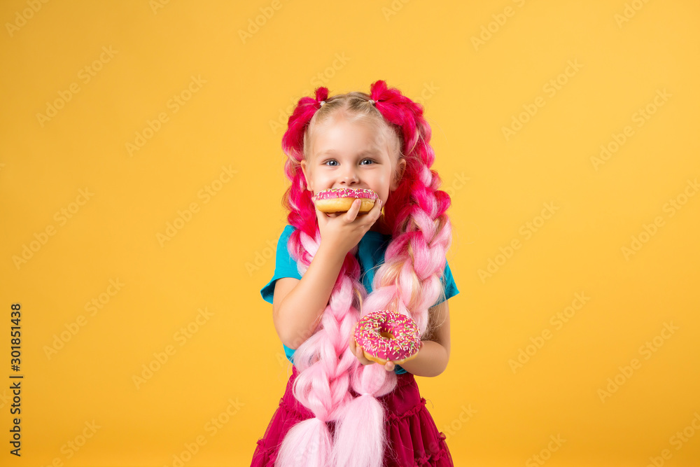 Fototapeta premium little girl with donuts on yellow background isolate, space for text