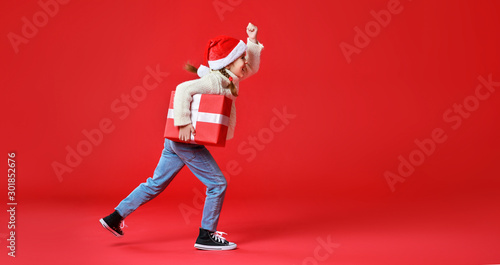happy funny child girl with Christmas gift on red background