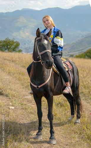  girl sitting on a horse on the background of the mountain landscape.