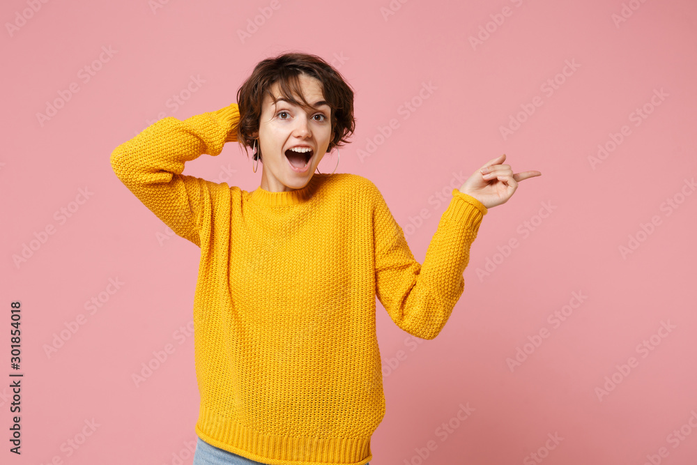 Excited young brunette woman girl in yellow sweater posing isolated on pastel pink background studio portrait. People lifestyle concept. Mock up copy space. Point index finger aside, put hand on head. Excited young brunette woman girl in yellow sweater posing isolated on pastel pink background studio portrait. People lifestyle concept. Mock up copy space. Point index finger aside, put hand on head.