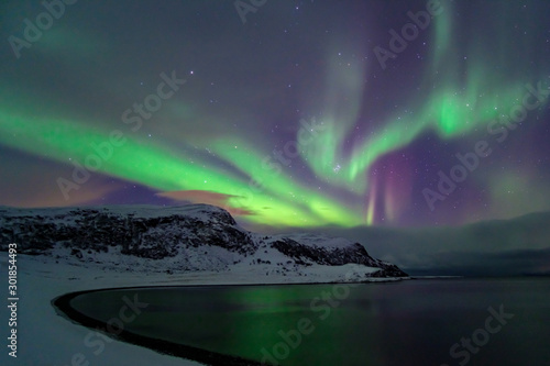 Intense northern lights  Aurora Borealis at a bay near Honningsvag and the Nordkapp  North Cape  Finnmark  Norway