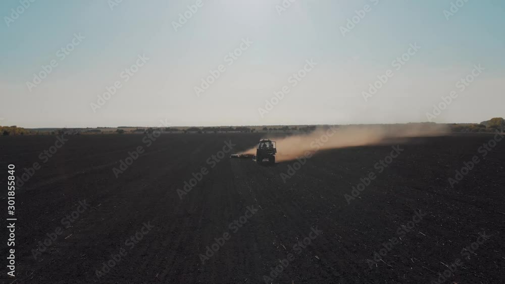 Aerial view modern tractor on the agricultural field on sunset time. Tractor plowing land and cultivating field.