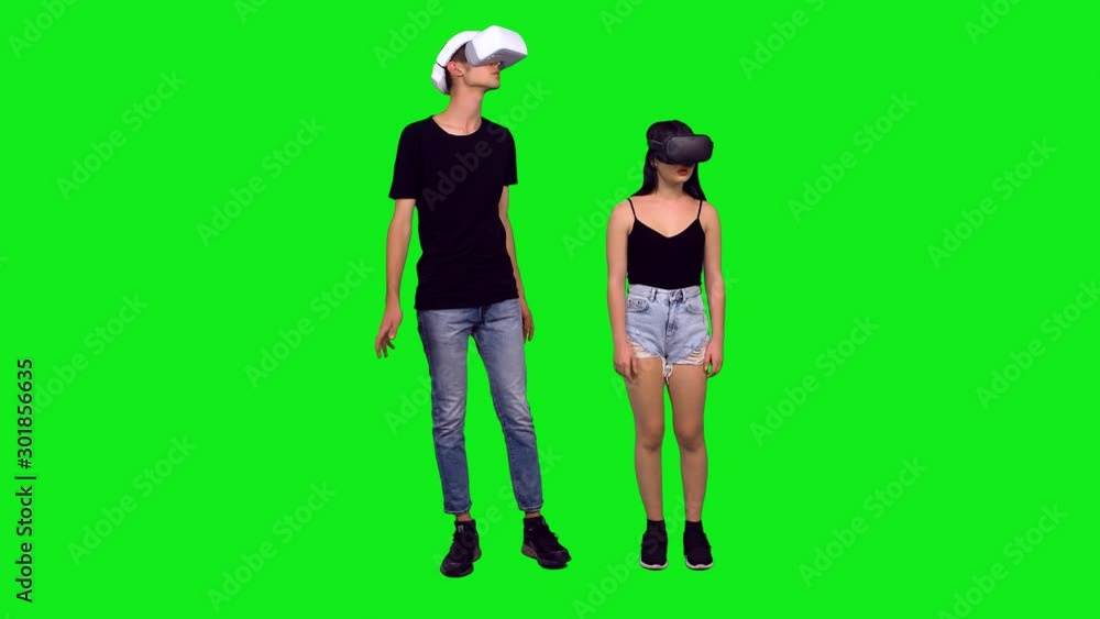 Teenagers with VR headsets, looking around at the same time while interacting with their environment. Full body shot over green screen. Teenagers with VR headsets, looking around at the same time while interacting with their environment. Full body shot over green screen.