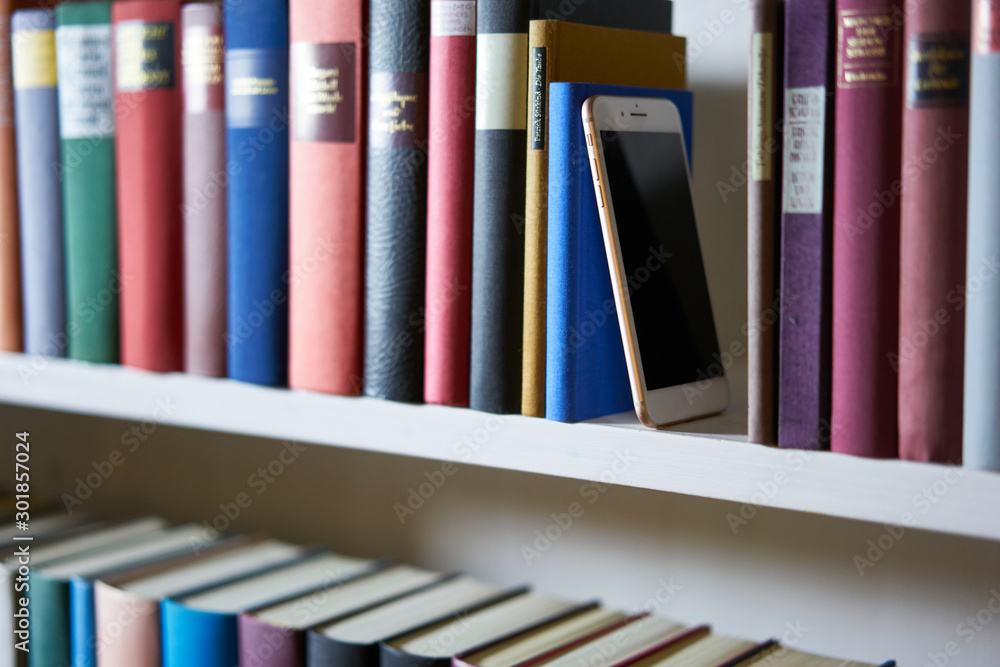 Mobile phone standing upright between books in bookcase Mobile phone standing upright between books in bookcase