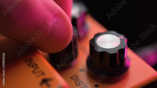 adjusting tone distortion knobs on a electric guitar effect pedal photo