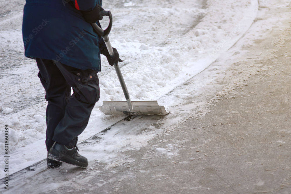 Worker shoveling snow on sidewalk after heavy snowfall. Municipal city service cleans footpath from snow and ice after blizzard. Janitor holds metal snow shovel in his hand and sweep snow from road Worker shoveling snow on sidewalk after heavy snowfall. Municipal city service cleans footpath from snow and ice after blizzard. Janitor holds metal snow shovel in his hand and sweep snow from road