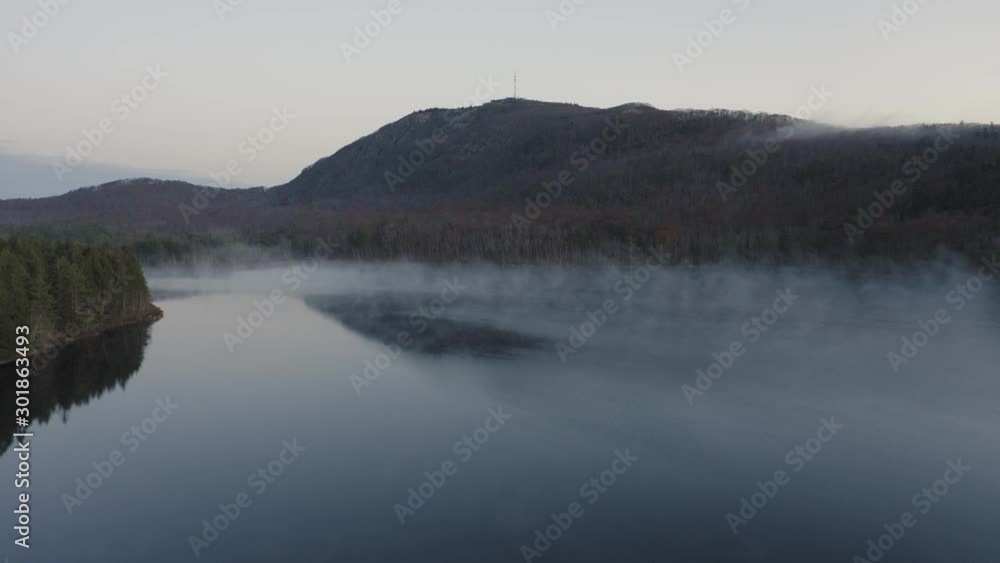 Sliding over the suface of a misty lake with a mountain in the distance AERIAL Sliding over the suface of a misty lake with a mountain in the distance AERIAL