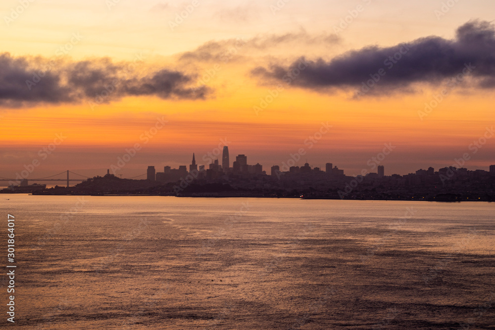Sunset or sunrise through the clouds, dramatic sky above the city of San Francisco, city in shadow, photo of the horizon taken on the Golden Gate