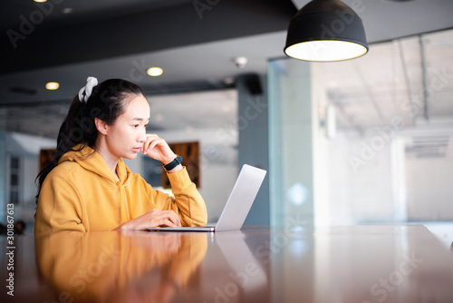 Beautiful asian woman using a notebook or laptop computer at coffee shop.l ifestyle freelance concept.copy space. photo