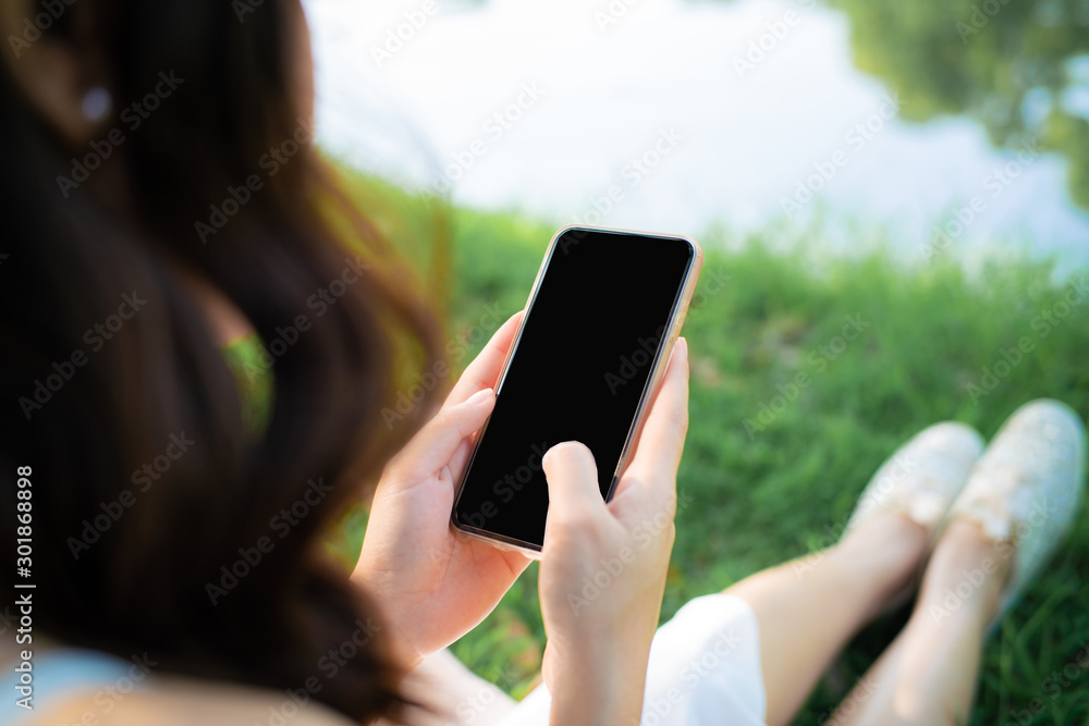 Beautiful women sitting on green grass use smartphone